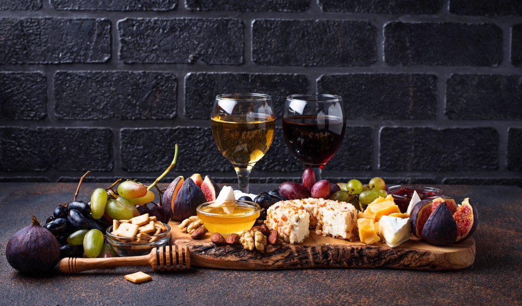 Два бокала вина на столе с сыром, инжиром и виноградом