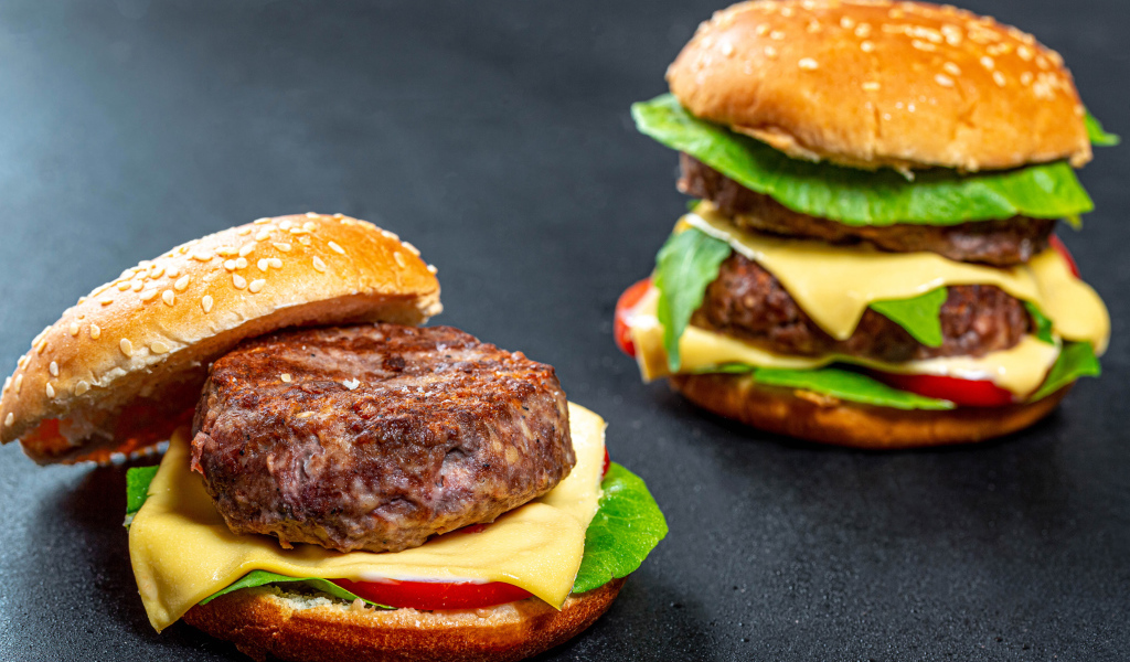 Два гамбургера с большой котлетой на столе