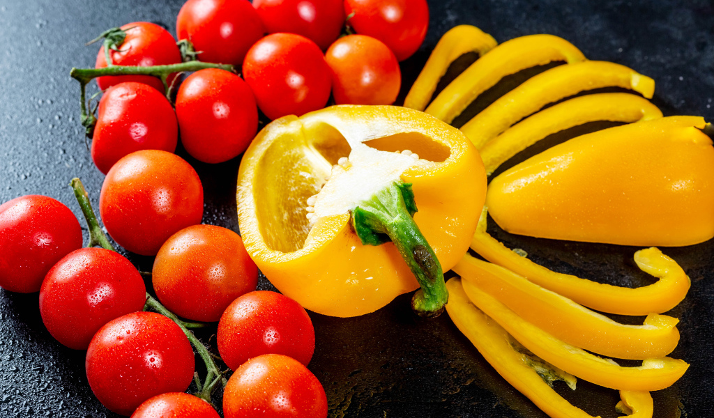 Желтый болгарский перец на столе с красными помидорами