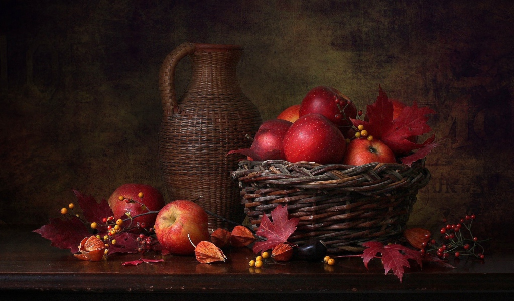 Корзина с красными яблоками на столе с кувшином 