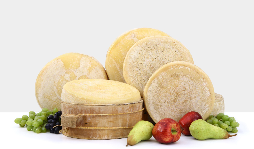 Сыр на столе с грушами, яблоками и виноградом