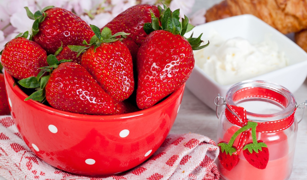 Свежие ягоды клубники в красной миске на столе