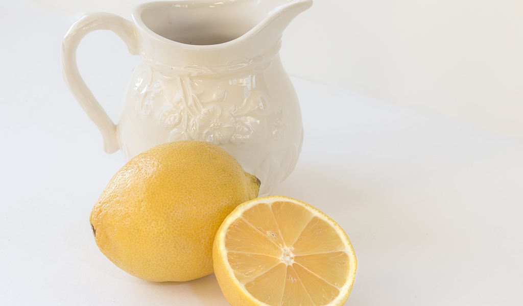 Лимон с белым кувшином на сером фоне