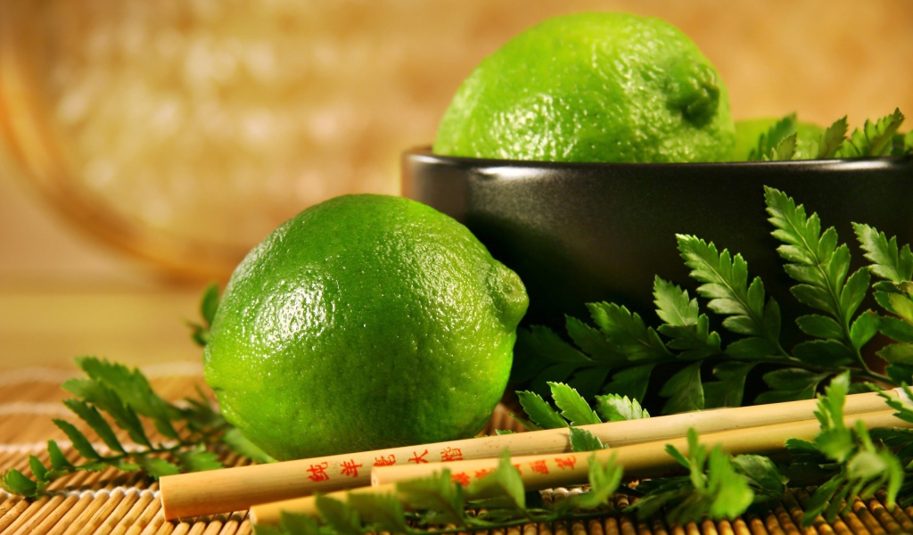 Лаймы на столе с палочками и листьями