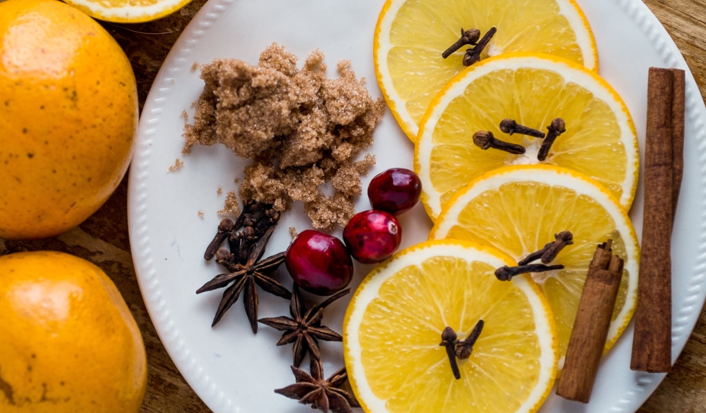 Круги апельсина на тарелке с сахаром, корицей и бадьяном