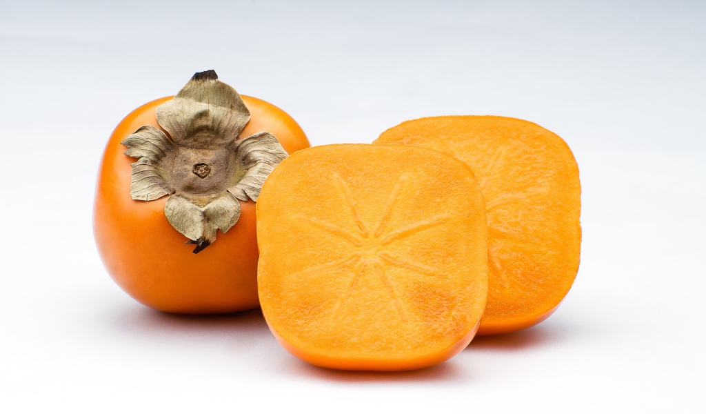 Оранжевая хурма на сером фоне крупным планом