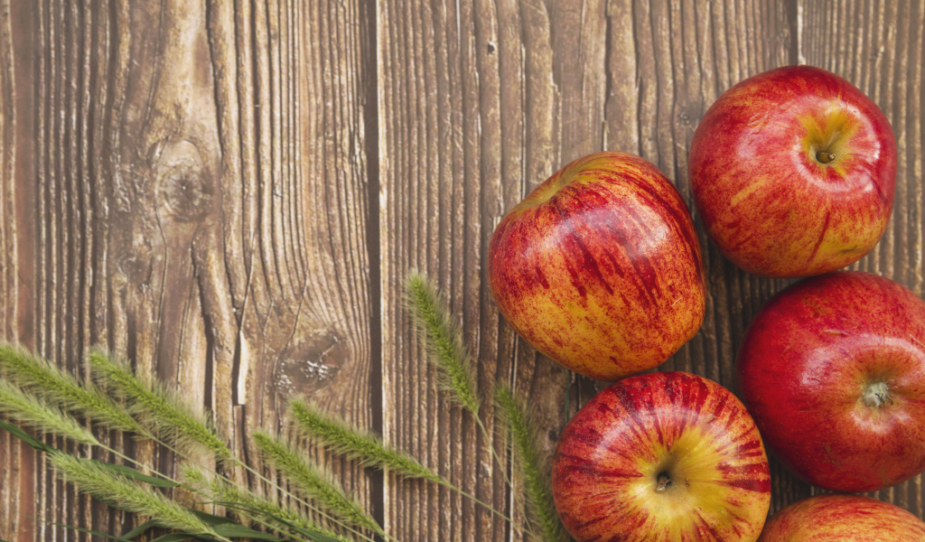 Красные яблоки на деревянном фоне с зелеными колосками