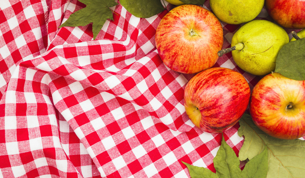 Красные яблоки с грушами на клетчатом покрывале