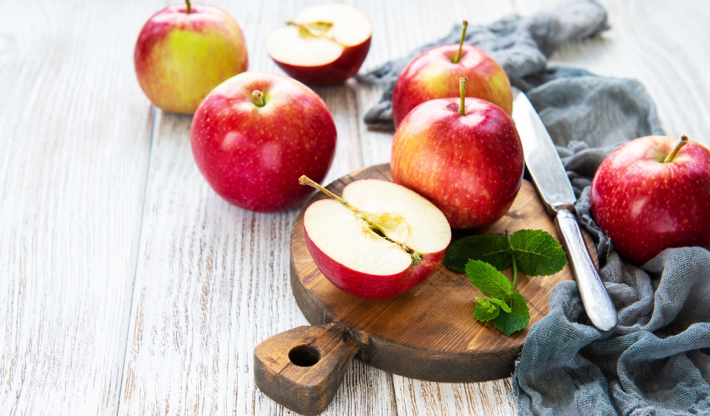 Спелые красные яблоки на разделочной доске с ножом