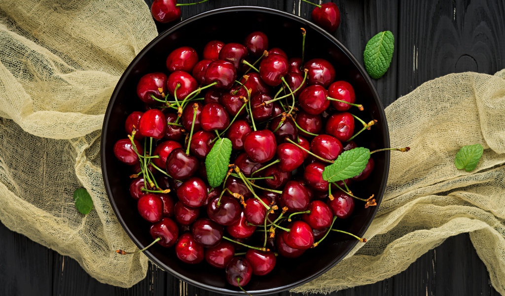 Спелые красные черешни в миске на столе