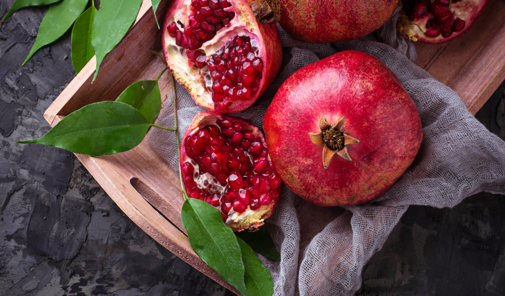 Спелые красные гранаты в деревянном ящике