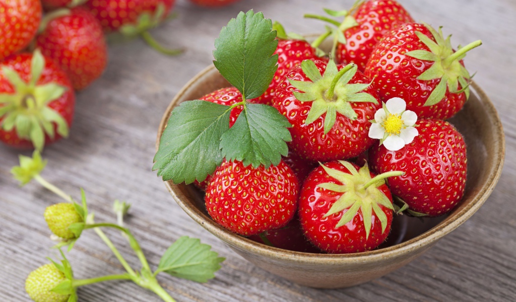 Спелая красная клубника в миске на столе 