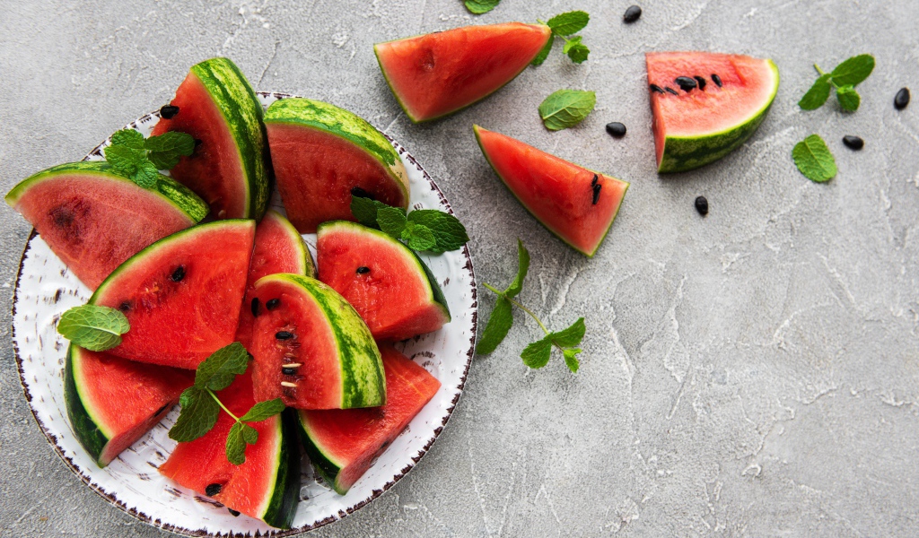 Полосатый арбуз нарезан кусочками на тарелке