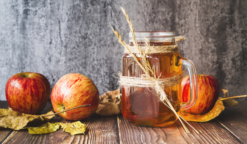 Три яблока с медом на столе на сером фоне