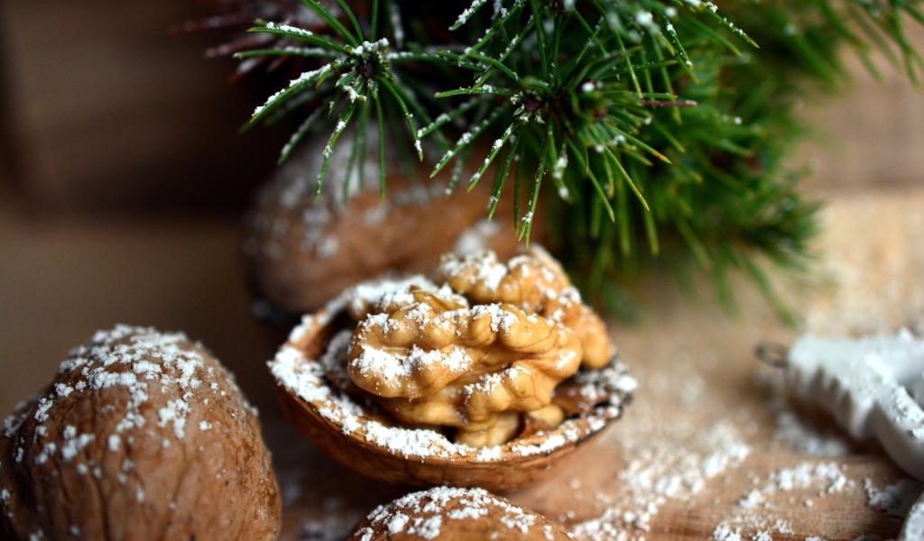 Грецкие орехи посыпанные сахарной пудрой на столе с еловой веткой