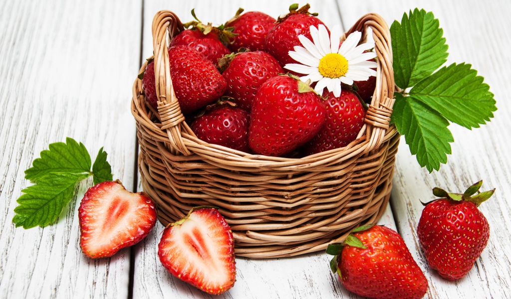 Плетеная корзинка с клубникой, ромашкой и зелеными листьями