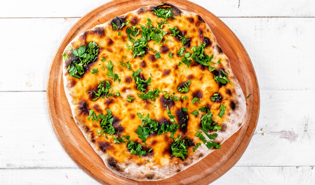 Пирог с сыром и зеленью на доске 