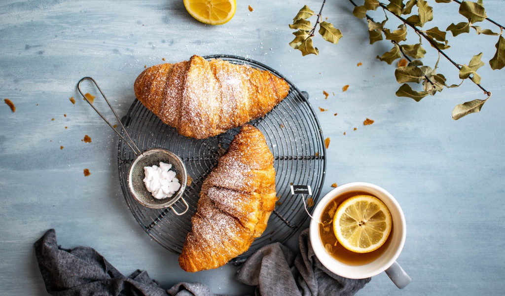 Два свежих круассана на столе с чаем