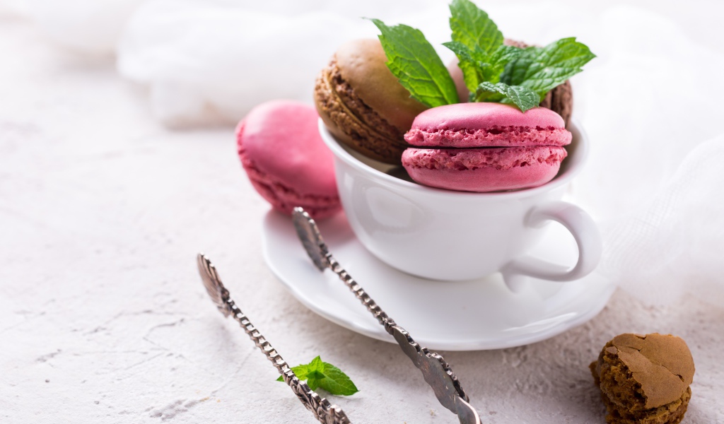 Разноцветный десерт макарун в белой чашке на столе