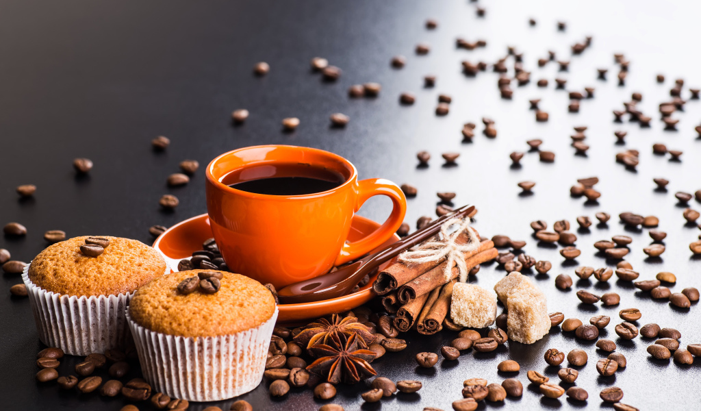 Чашка кофе на столе с кексами, кофейными зернами, корицей и бадьяном