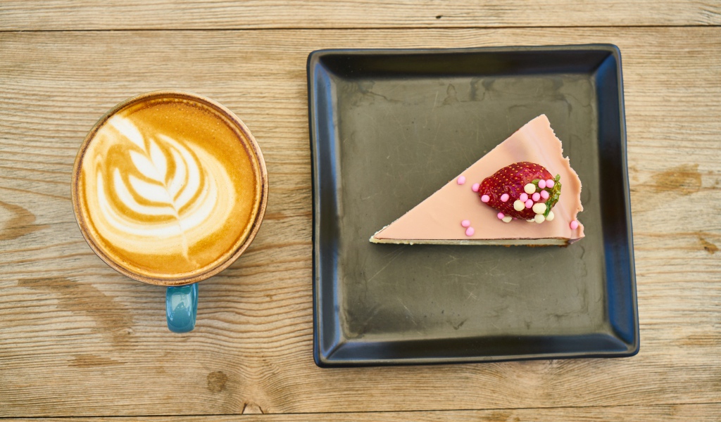 Кусок торта на черной тарелке с кофе