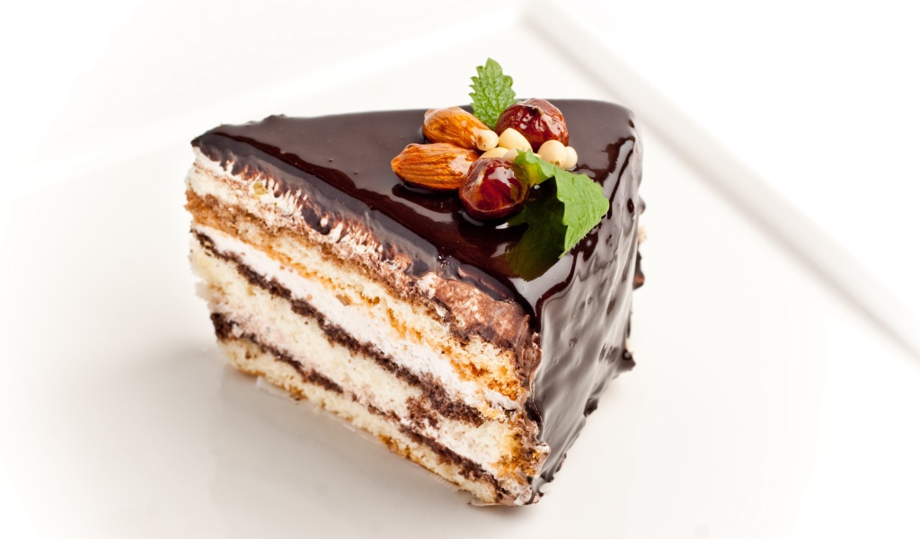 Кусок торта с шоколадом и орехами на белом фоне