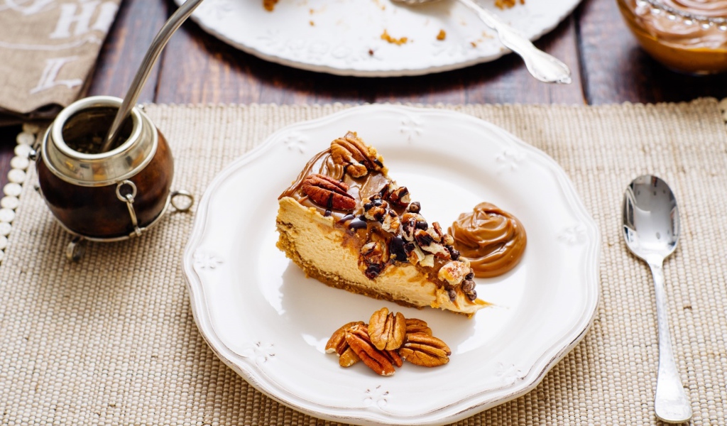 Кусок торта с орехами на белой тарелке на столе с кофе