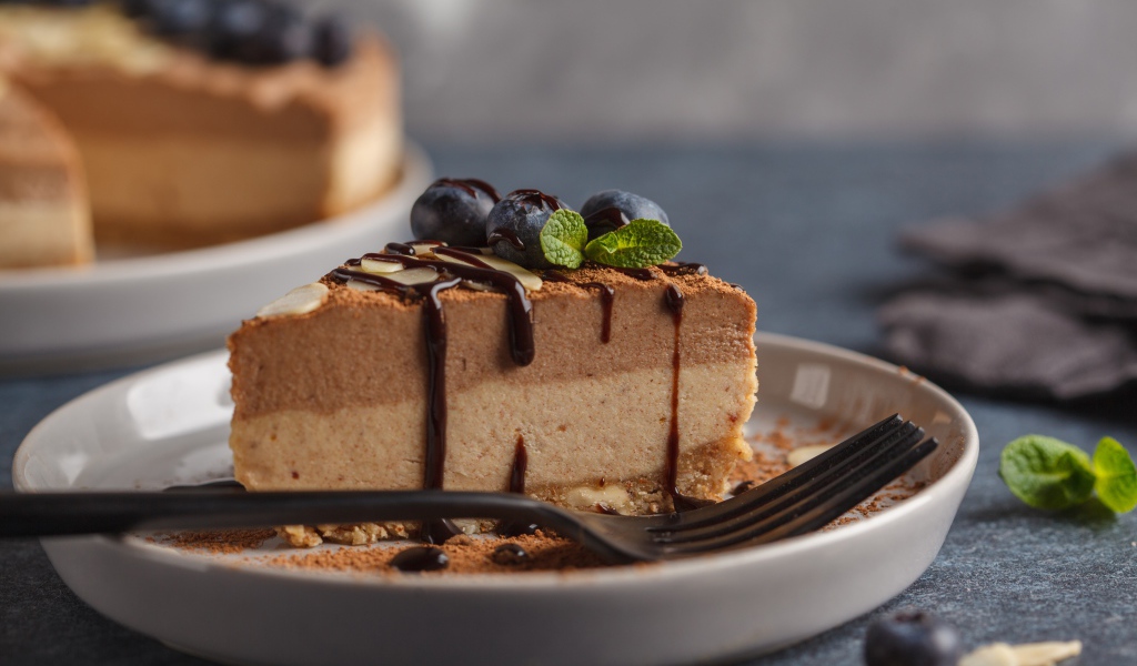 Кусок чизкейка с черникой и шоколадом на тарелке с вилкой