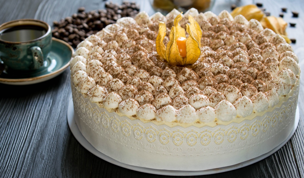 Красивый праздничный торт с цветком физалиса на столе с кофе