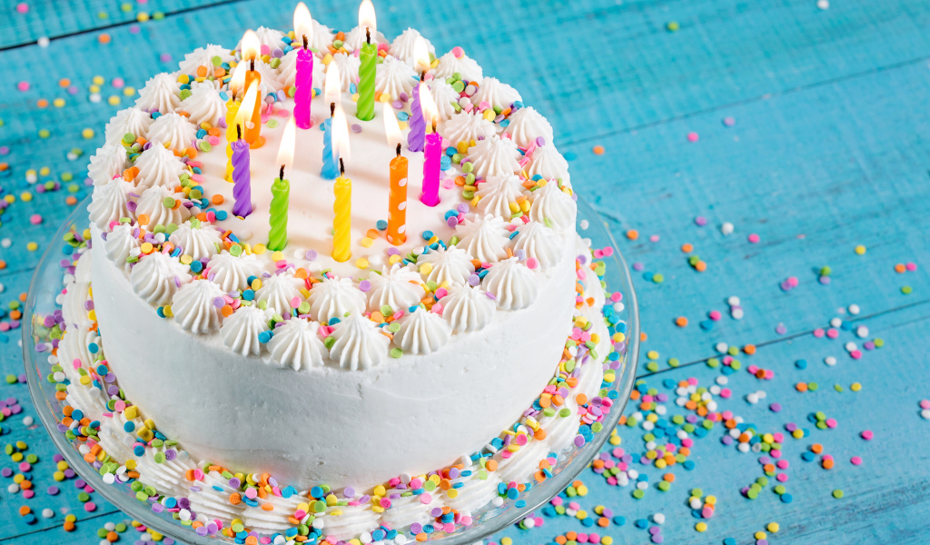 Большой праздничный торт с кремом и свечами на голубом столе