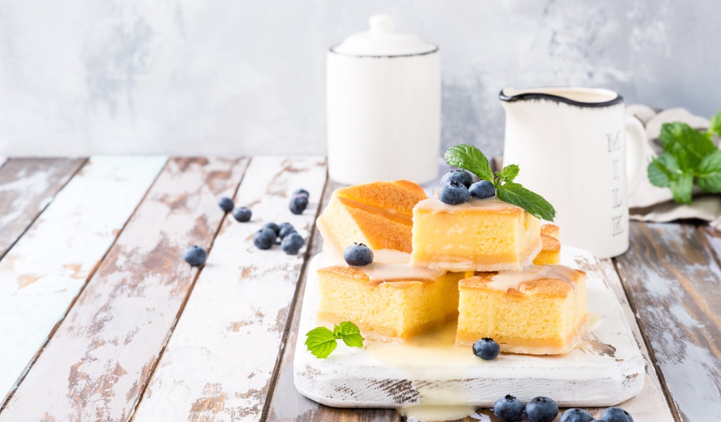 Кусочки бисквитного пирожного на столе с ягодами черники