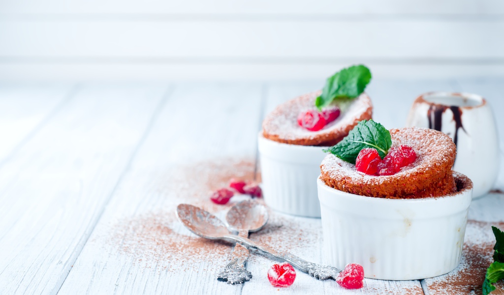 Пирожное с ягодами и сахарной пудрой на столе с ложками