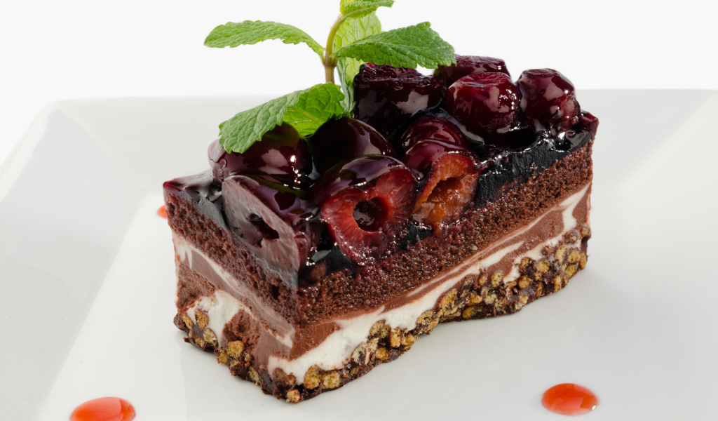 Пирожное с черешней и листиками мяты на сером фоне