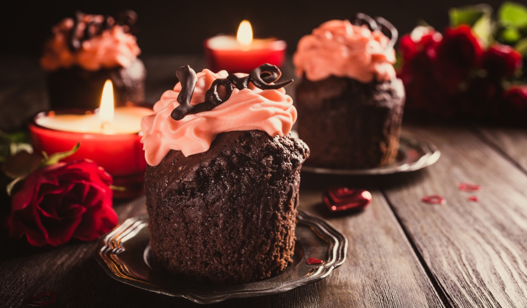 Шоколадные кексы с кремом на столе со свечами и розами