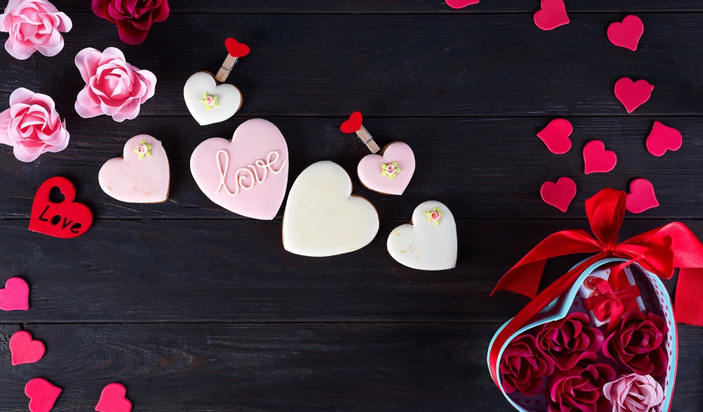 Печенье с глазурью на черной поверхности с сердечками и подарком