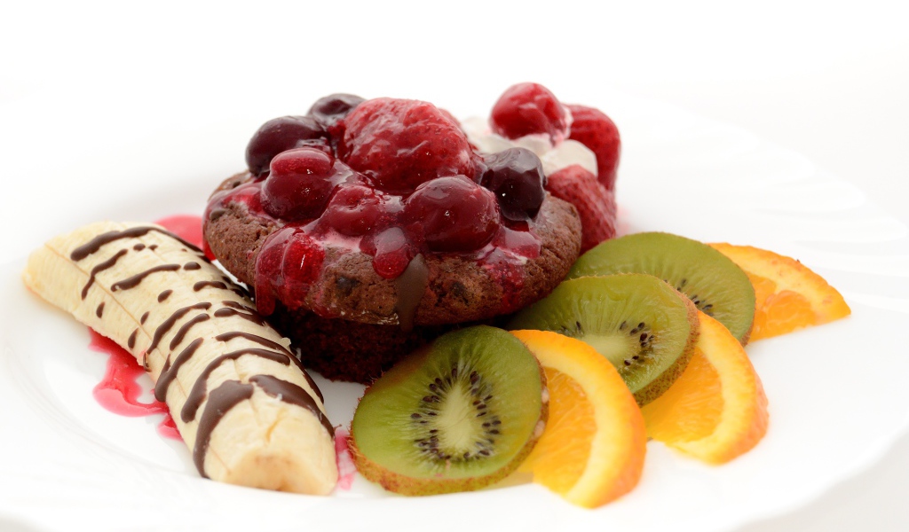 Печенье с вареньем, кусочками банана, киви и апельсина на белом фоне