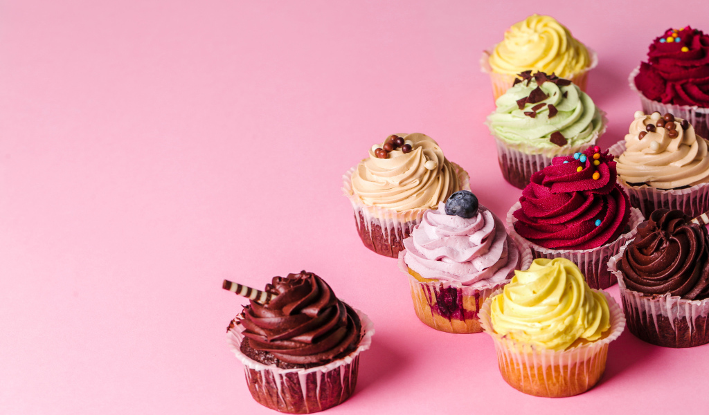 Кексы с разноцветным кремом на розовом фоне