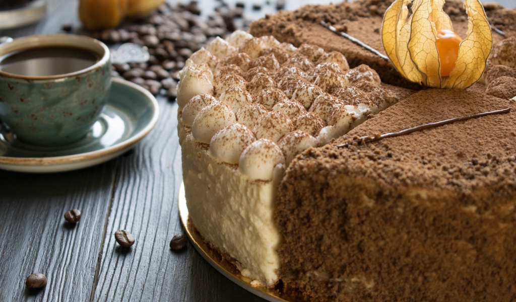 Вкусный торт с кремом и физалисом на столе с кофе