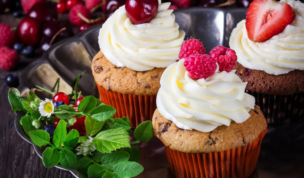 Аппетитные кексы с кремом и ягодами на блюде