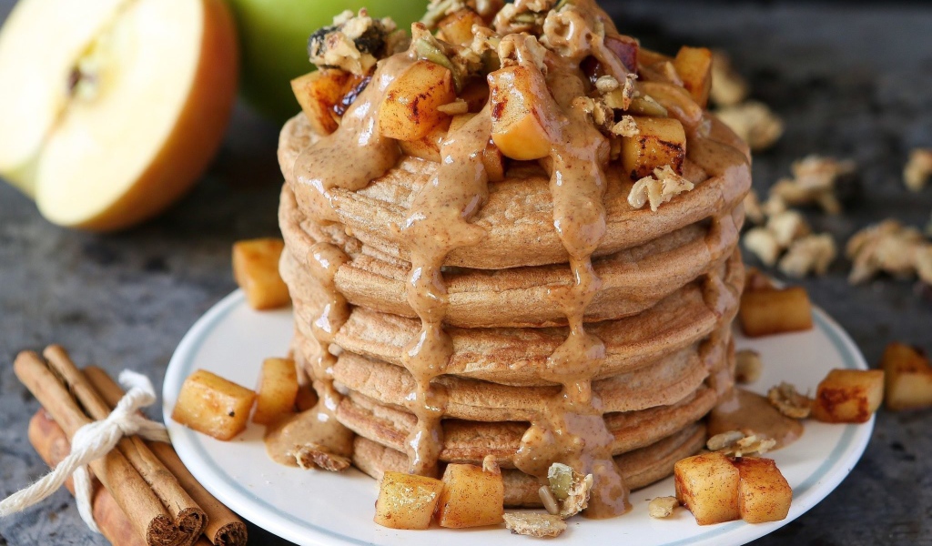 Вкусные оладьи с соусом и фруктами на столе с корицей