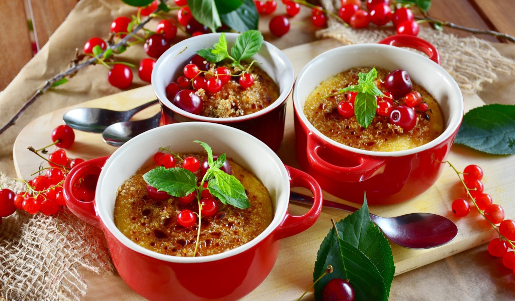 Десерт в красной посуде на столе с вишней и красной смородиной