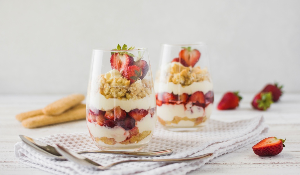 Десерт с клубникой в стеклянных стаканах на столе 