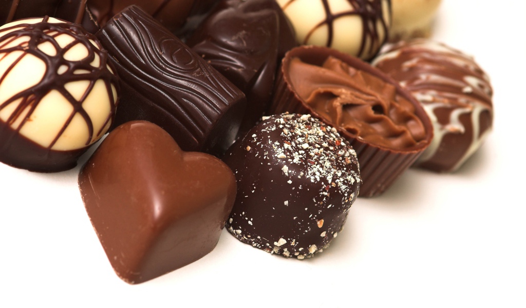 Разные шоколадные конфеты на белом фоне 