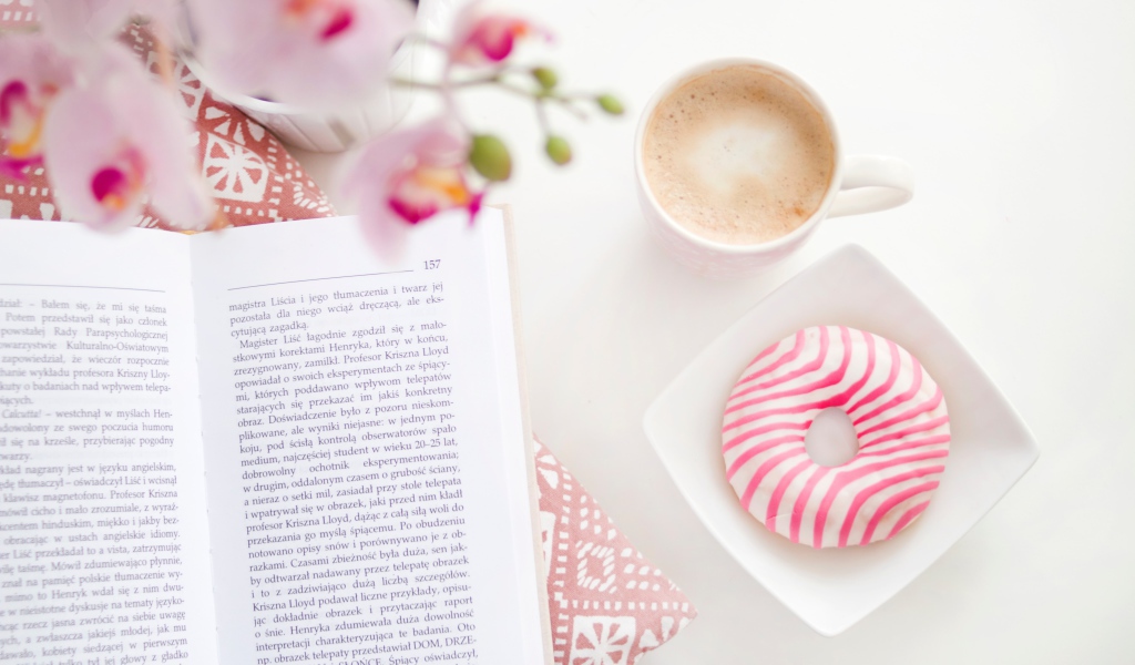 Пончик с чашкой кофе на столе с книгой
