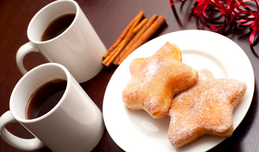 Пончики на столе с кофе и палочками корицы