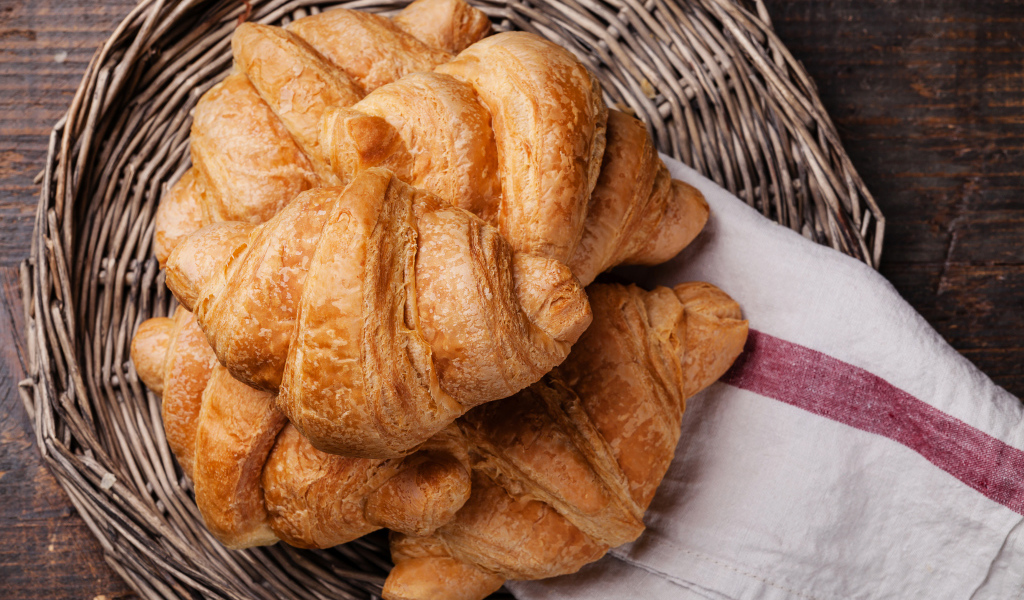 Свежие круассаны в корзинке с полотенцем