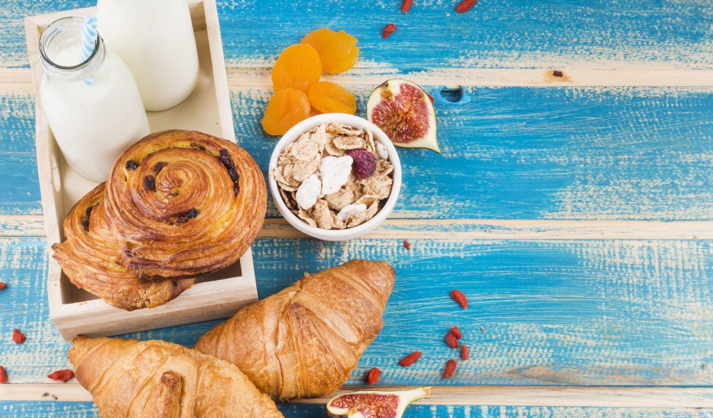 Свежая выпечка, молоко и мюсли на завтрак на столе