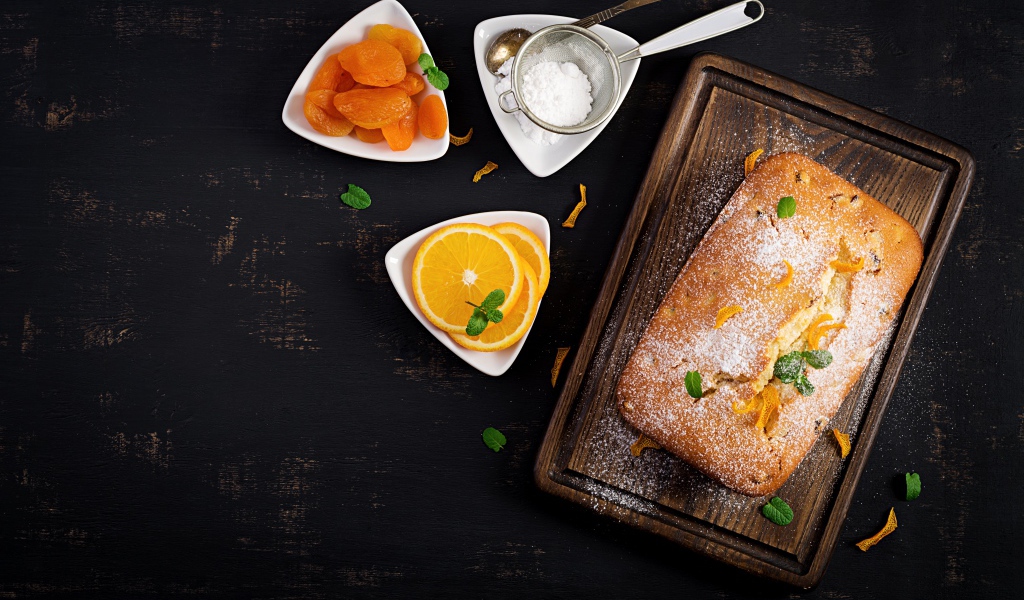 Свежий сладкий пирог на столе с курагой и апельсином