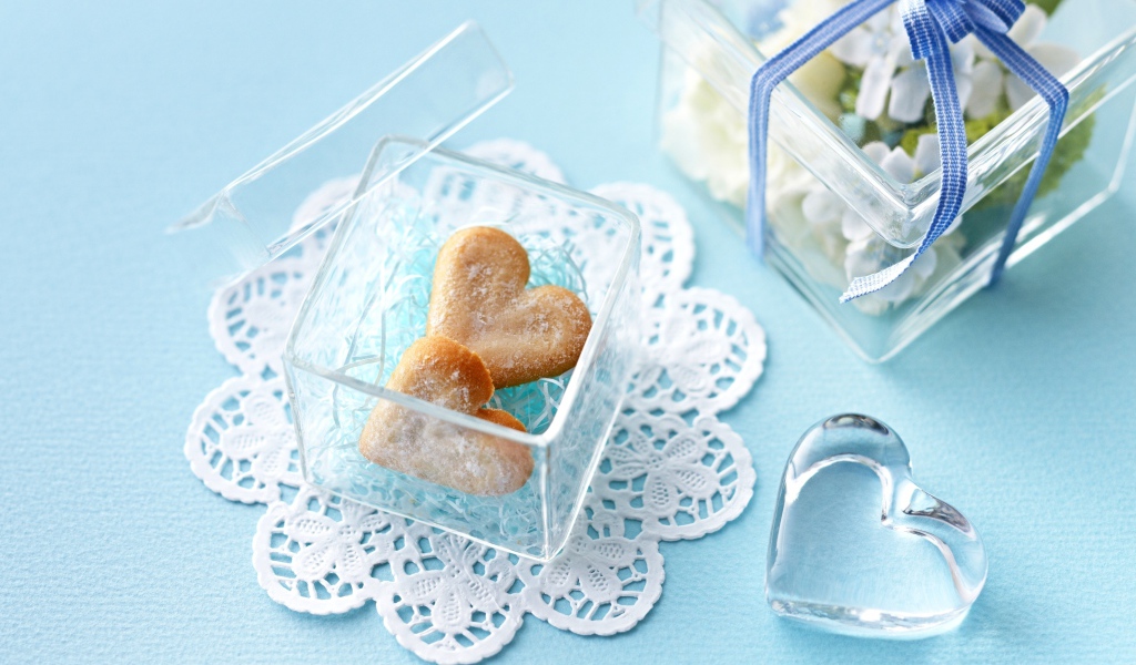 Песочное печенье в форме сердца в стеклянной шкатулке на голубом столе 