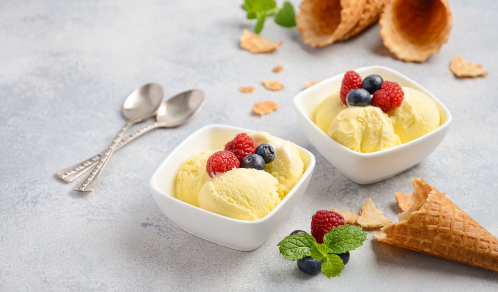 Шарики мороженого с ягодами на столе с вафельными рожками